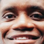 Close-up shot of a smiling man on a black background, showcasing a joyful expression.